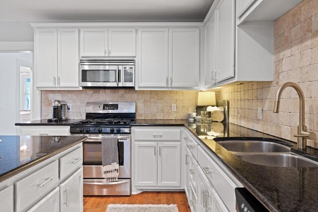 kitchen featuring a sink, light wood-style flooring, stainless steel appliances, and white cabinetry