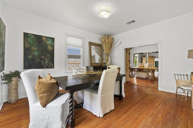 dining room featuring visible vents, a healthy amount of sunlight, and wood finished floors