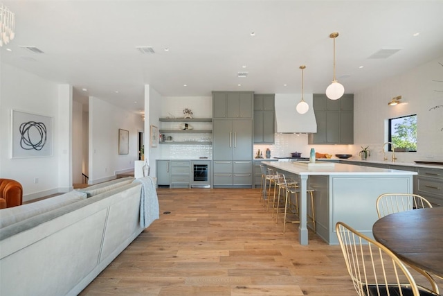5914 Cape Coral Dr, Austin, TX 78746 - kitchen with gray cabinetry, beverage cooler, tasteful backsplash, light wood-style flooring, and recessed lighting