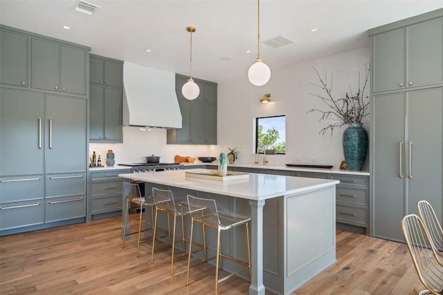 5914 Cape Coral Dr, Austin, TX 78746 - kitchen featuring premium range hood, light wood finished floors, a center island, light countertops, and a breakfast bar