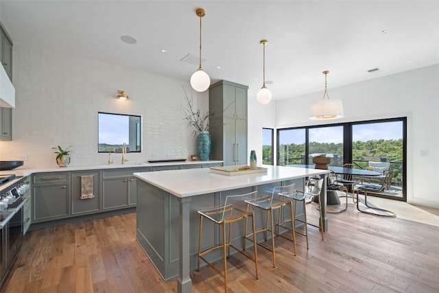 5914 Cape Coral Dr, Austin, TX 78746 - kitchen with gray cabinets, wood finished floors, light countertops, a kitchen island, and backsplash