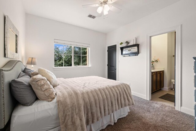 bedroom with a ceiling fan, light colored carpet, visible vents, baseboards, and connected bathroom