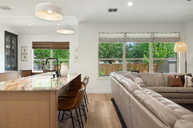 living room featuring recessed lighting, baseboards, visible vents, and light wood-type flooring