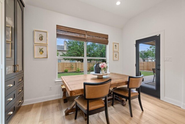 dining space with baseboards, vaulted ceiling, a wealth of natural light, and light wood finished floors
