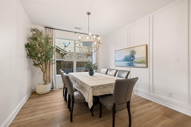 dining space featuring visible vents, light wood-style flooring, baseboards, and a chandelier