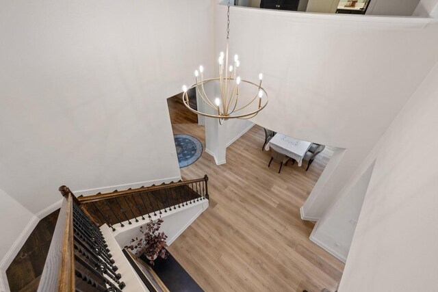 stairs featuring an inviting chandelier, baseboards, and wood finished floors