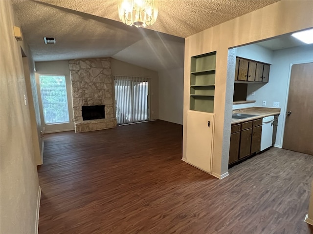 8105 Dowling Cv, Austin, TX 78745 - kitchen with white dishwasher, dark wood-style floors, a textured ceiling, lofted ceiling, and a stone fireplace