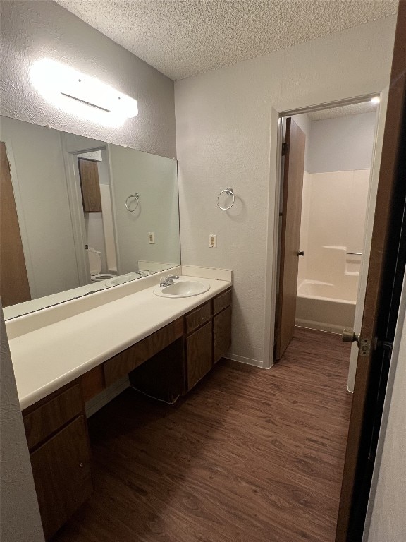 8105 Dowling Cv, Austin, TX 78745 - bathroom with a textured ceiling, wood finished floors, vanity, and a textured wall