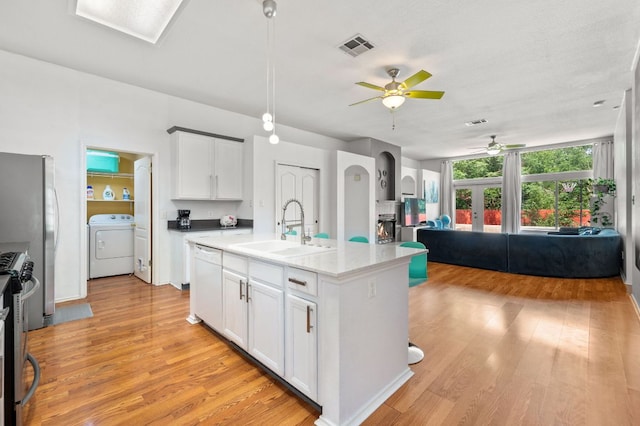 kitchen with ceiling fan, a sink, stainless steel appliances, open floor plan, and washer / dryer