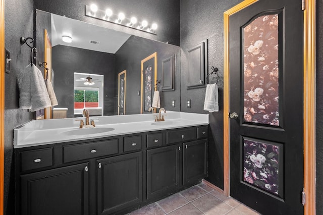 full bath with a sink, a textured wall, and tile patterned floors
