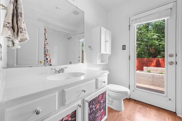 full bath featuring a shower with shower curtain, wood finished floors, a wealth of natural light, and toilet