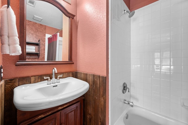 full bathroom featuring a textured wall, visible vents, shower / bath combo, and vanity