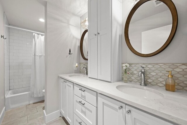 bathroom featuring a sink, backsplash, double vanity, and visible vents