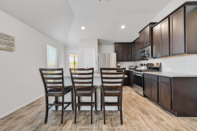 155 Lyndon Dr, San Marcos, TX 78666 - kitchen with dark brown cabinets, light wood-style floors, a kitchen breakfast bar, stainless steel appliances, and a kitchen island