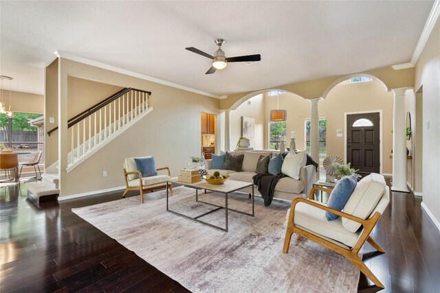 living room featuring ceiling fan, stairway, baseboards, wood-type flooring, and ornate columns