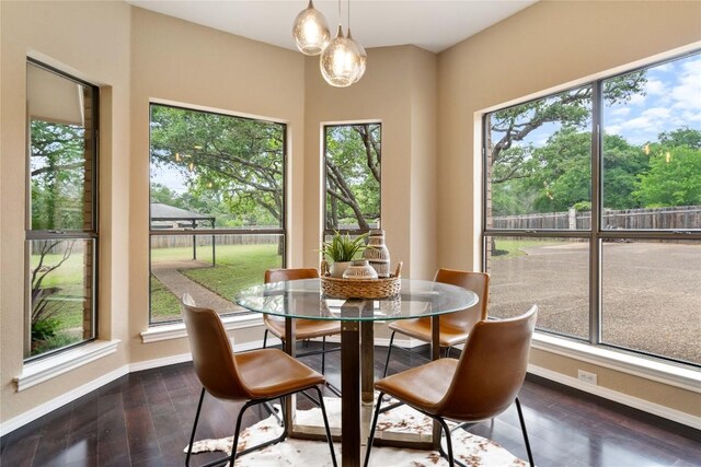 dining space featuring dark wood-style flooring, baseboards, a notable chandelier, and plenty of natural light
