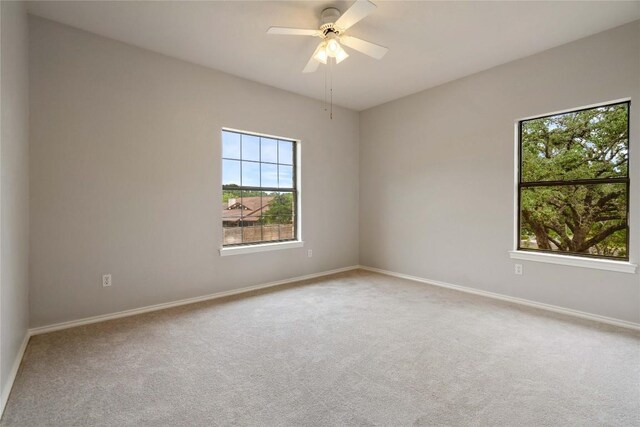 spare room with baseboards, ceiling fan, and carpet