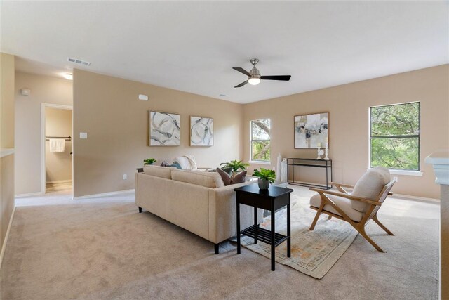 living area with baseboards, a ceiling fan, light colored carpet, and visible vents