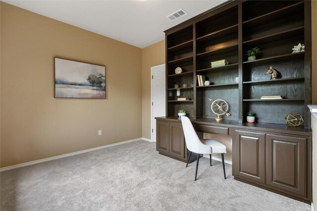 home office featuring baseboards, visible vents, light carpet, and built in study area