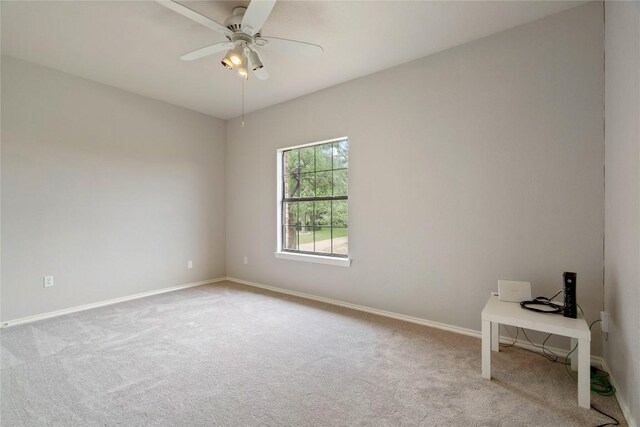 carpeted empty room with a ceiling fan and baseboards
