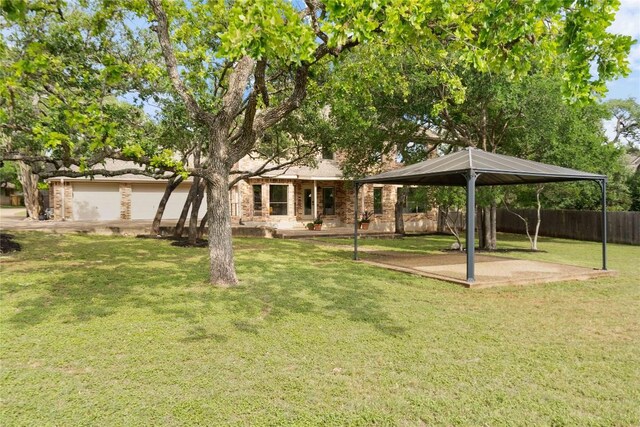 view of front facade with fence, a gazebo, a front lawn, brick siding, and a patio area