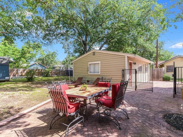 1128 W Hopkins St, San Marcos, TX 78666 - view of patio / terrace with an outdoor structure, a gate, outdoor dining area, and a fenced backyard
