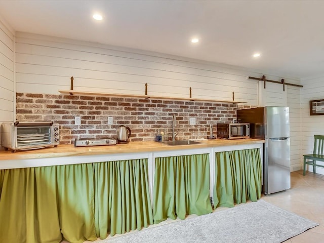 1128 W Hopkins St, San Marcos, TX 78666 - kitchen featuring a barn door, a sink, light tile patterned floors, a toaster, and stainless steel appliances