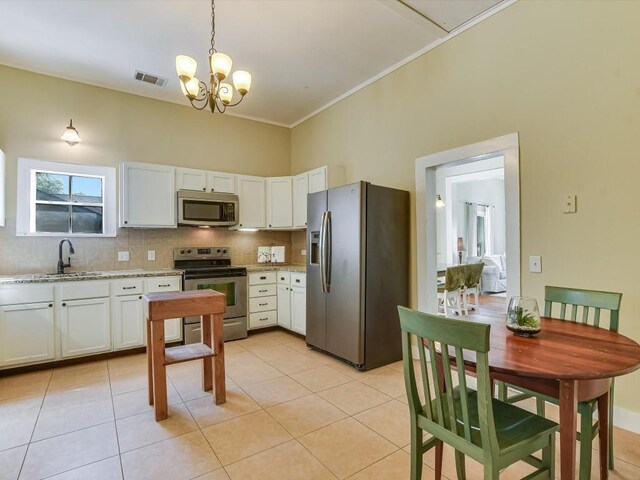 1128 W Hopkins St, San Marcos, TX 78666 - kitchen featuring visible vents, tasteful backsplash, light tile patterned floors, a notable chandelier, and stainless steel appliances