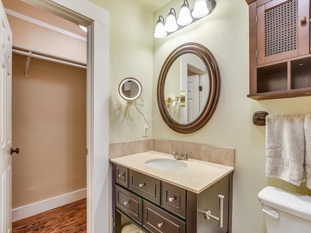 1128 W Hopkins St, San Marcos, TX 78666 - bathroom featuring vanity, baseboards, wood finished floors, and toilet