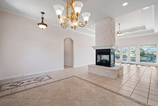 unfurnished living room with ornamental molding, arched walkways, and a tray ceiling