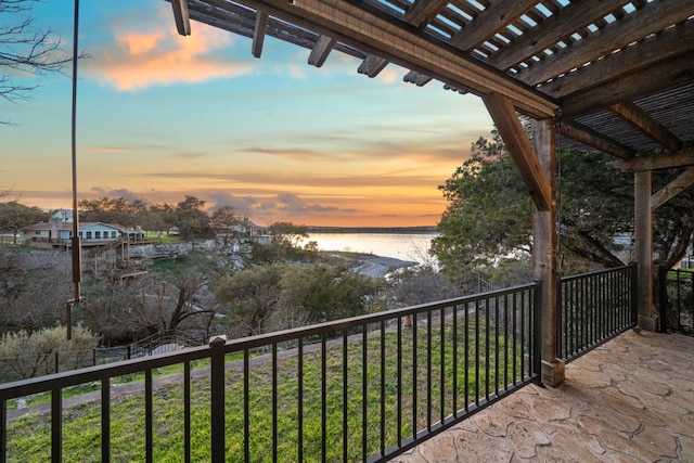 balcony at dusk with a pergola and a water view