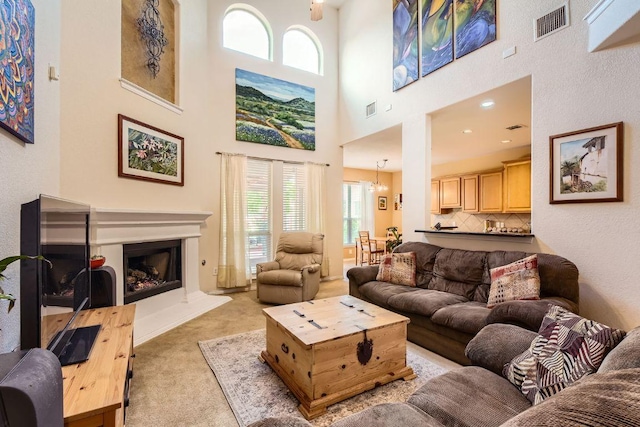 living area featuring light colored carpet, visible vents, plenty of natural light, and a towering ceiling