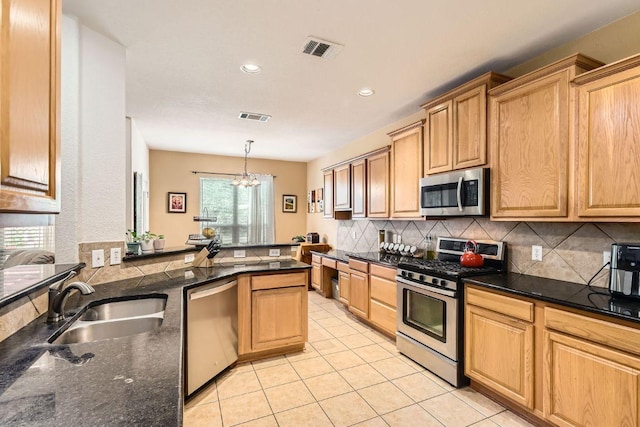 kitchen with a sink, appliances with stainless steel finishes, decorative backsplash, and visible vents