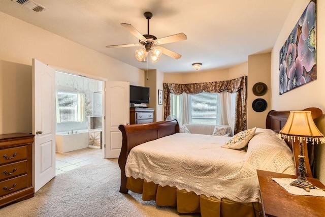 bedroom with visible vents, ensuite bath, light carpet, and multiple windows