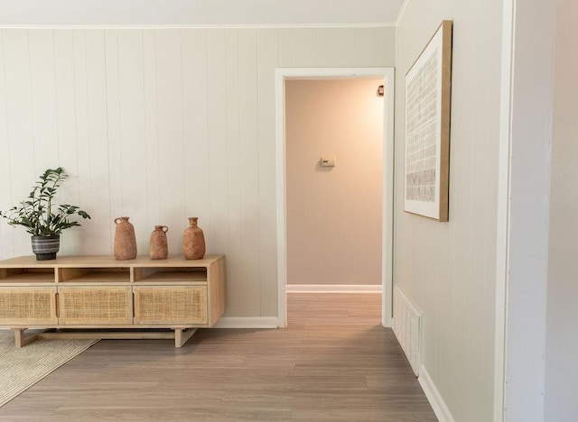 corridor with crown molding, baseboards, wood finished floors, and visible vents