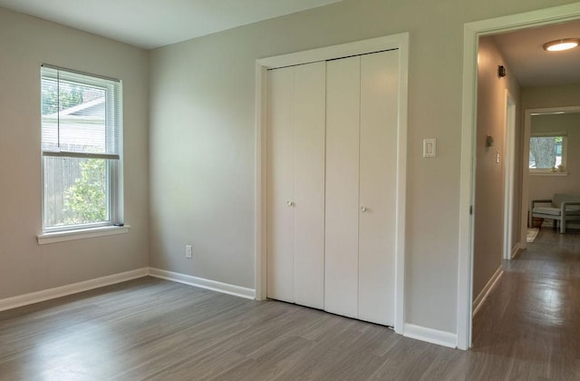unfurnished bedroom with baseboards, a closet, and wood finished floors