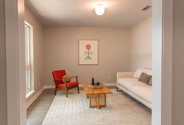 living area featuring baseboards, wood finished floors, and visible vents