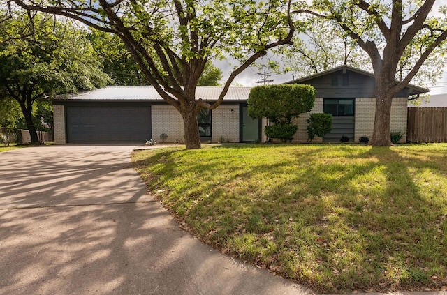 single story home with a front lawn, fence, brick siding, an attached garage, and driveway