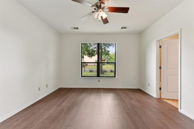 spare room featuring baseboards, ceiling fan, visible vents, and wood finished floors