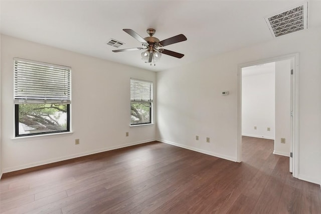 empty room featuring baseboards, ceiling fan, dark wood-style floors, and visible vents