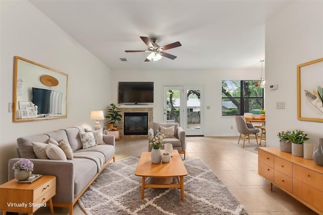 living room with visible vents, a ceiling fan, a glass covered fireplace, and light tile patterned flooring