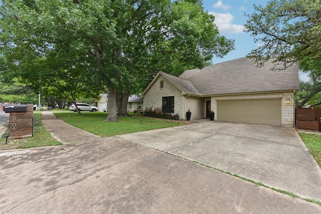 ranch-style home featuring an attached garage, a front yard, driveway, and stone siding