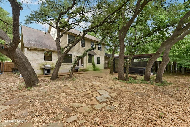 exterior space with fence, a patio area, and stone siding