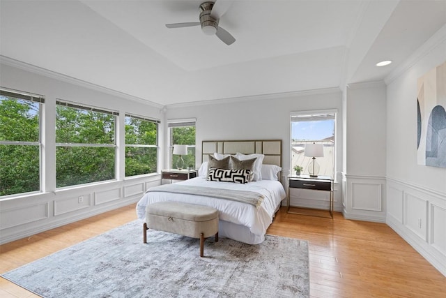 bedroom with a decorative wall, a wainscoted wall, a ceiling fan, wood finished floors, and ornamental molding