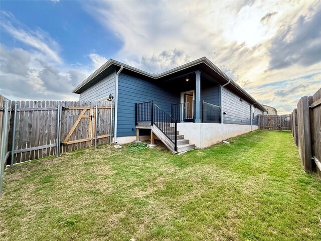rear view of house with a fenced backyard and a yard