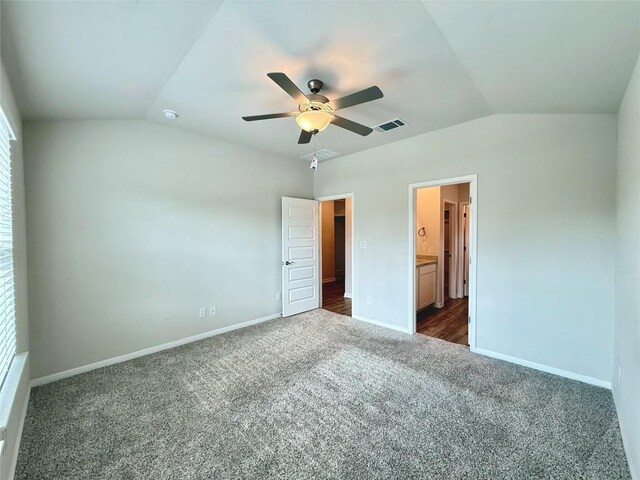 unfurnished bedroom with baseboards, visible vents, dark carpet, and lofted ceiling