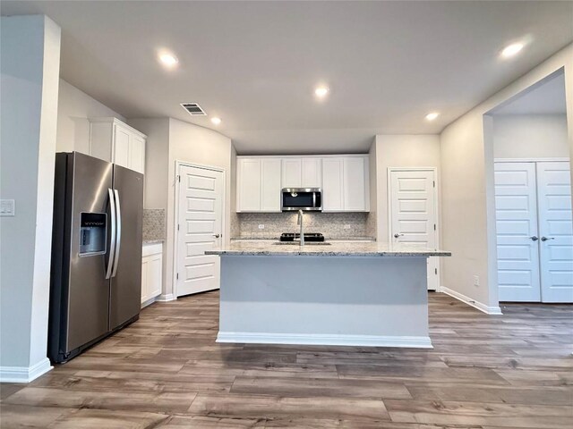kitchen with visible vents, decorative backsplash, dark wood-style flooring, and stainless steel appliances