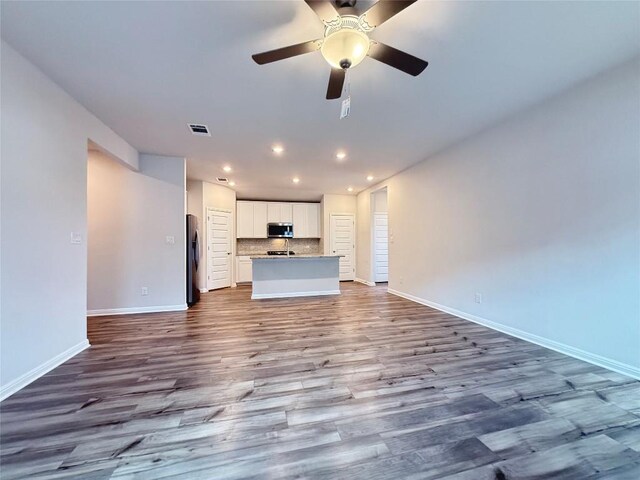 unfurnished living room featuring baseboards, recessed lighting, wood finished floors, and visible vents