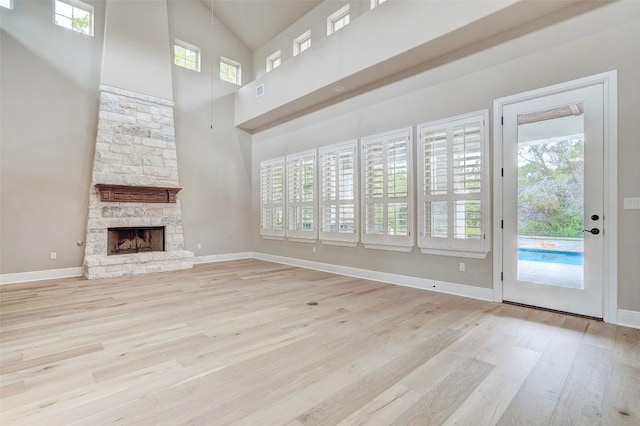 423 Bella Montagna Cir, Austin, TX 78734 - unfurnished living room featuring light wood-style flooring, a towering ceiling, and a stone fireplace