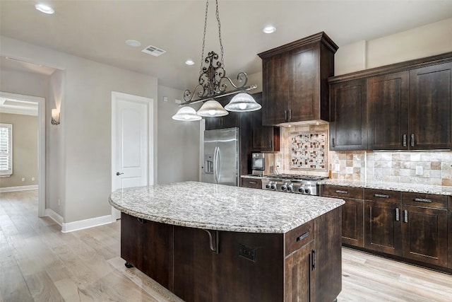 kitchen featuring visible vents, a kitchen island, stainless steel fridge with ice dispenser, light wood-style flooring, and backsplash